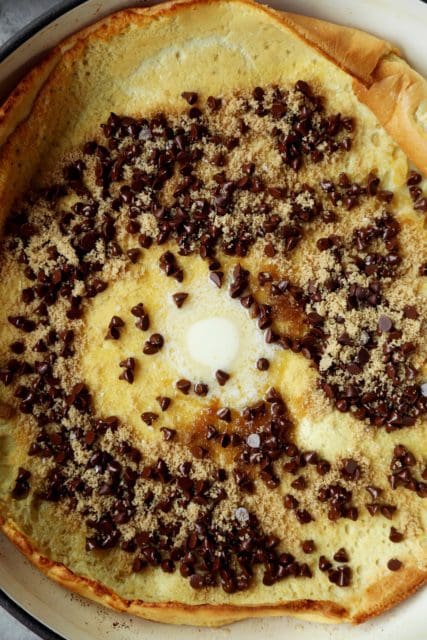 Close up of Dutch baby in pan with chocolate chips, brown sugar, and melted butter.