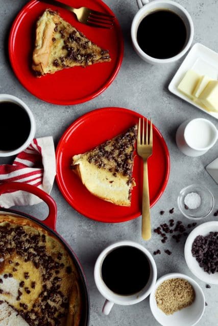 Slices. of warm. Dutch baby on red plates with coffee and butter.