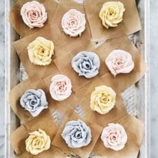 pastel colored buttercream roses on a baking sheet