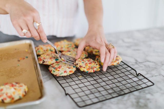 Spooning baked cookies onto baking sheet.