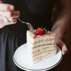 Slice of strawberry and pistachio doberge cake on a place with fork.
