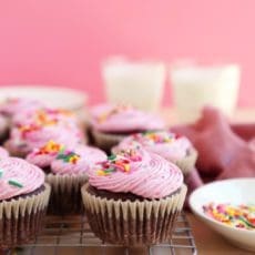 Glasses of milk and frosted small batch chocolate cupcakes on a wire rack