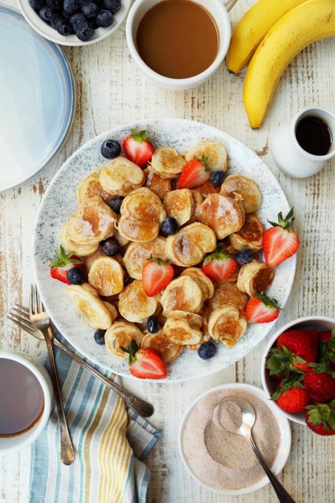 Platter of banana pancakes with sliced strawberries and fresh blueberries