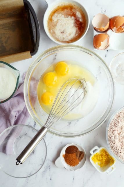 Eggs and sugar measured into a bowl with a whisk.