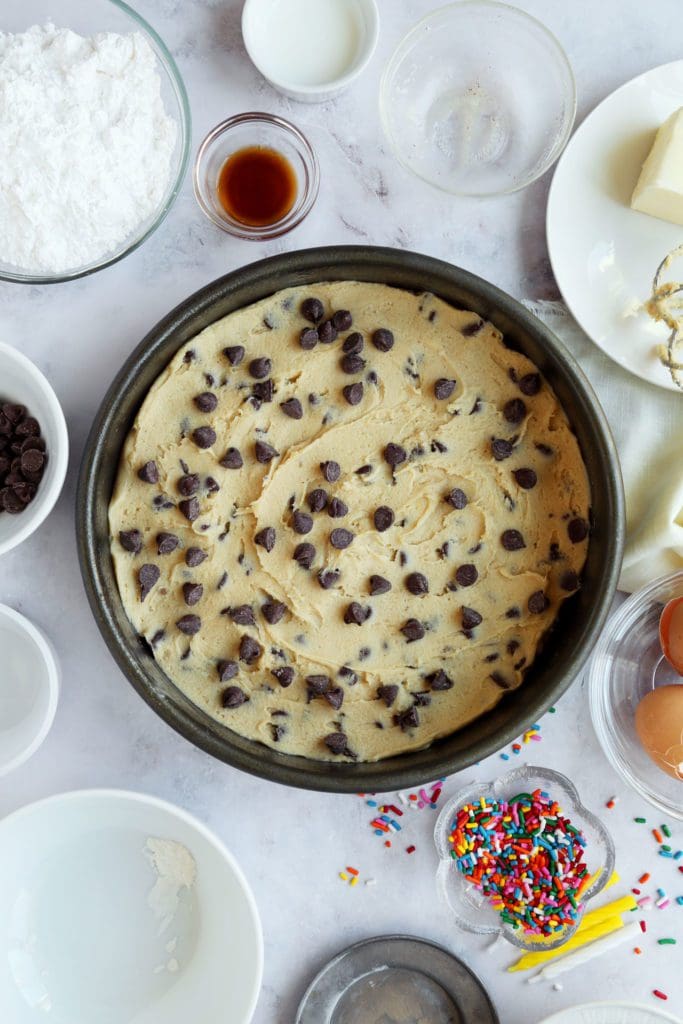Cookie batter added to 9-inch round pan with chocolate chips on top.
