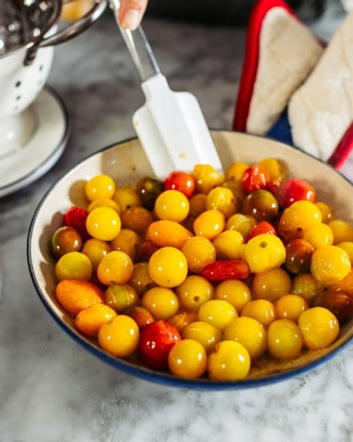 Golden cherry tomatoes cooking in cast iron pan for tomato pie recipe.