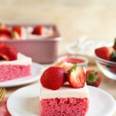 strawberry sheet cake on a plate with strawberries on top.