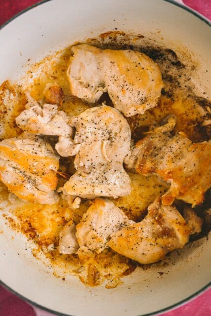browned chicken on a plate waiting to go in a pot