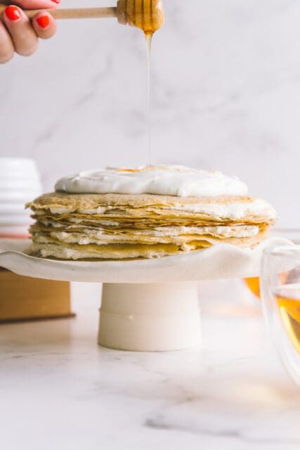 crepe cake with whipped cream on top on a cake stand with
