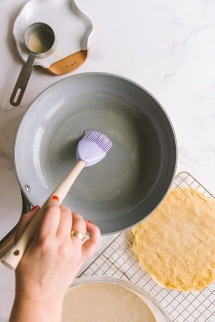 brushing pan with melted butter to pour crepe batter in