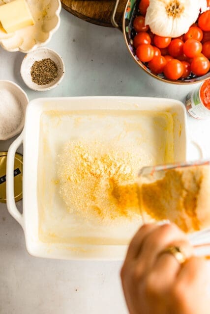 adding polenta into a dish to mix and bake