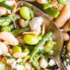 spoonful of spring salad with edamame, asparagus, cannellini beans, slivered almonds, and crumbled cheese