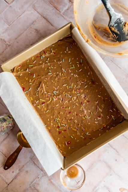 blondie batter in a parchment lined pan waiting to be baked for ice cream sandwiches